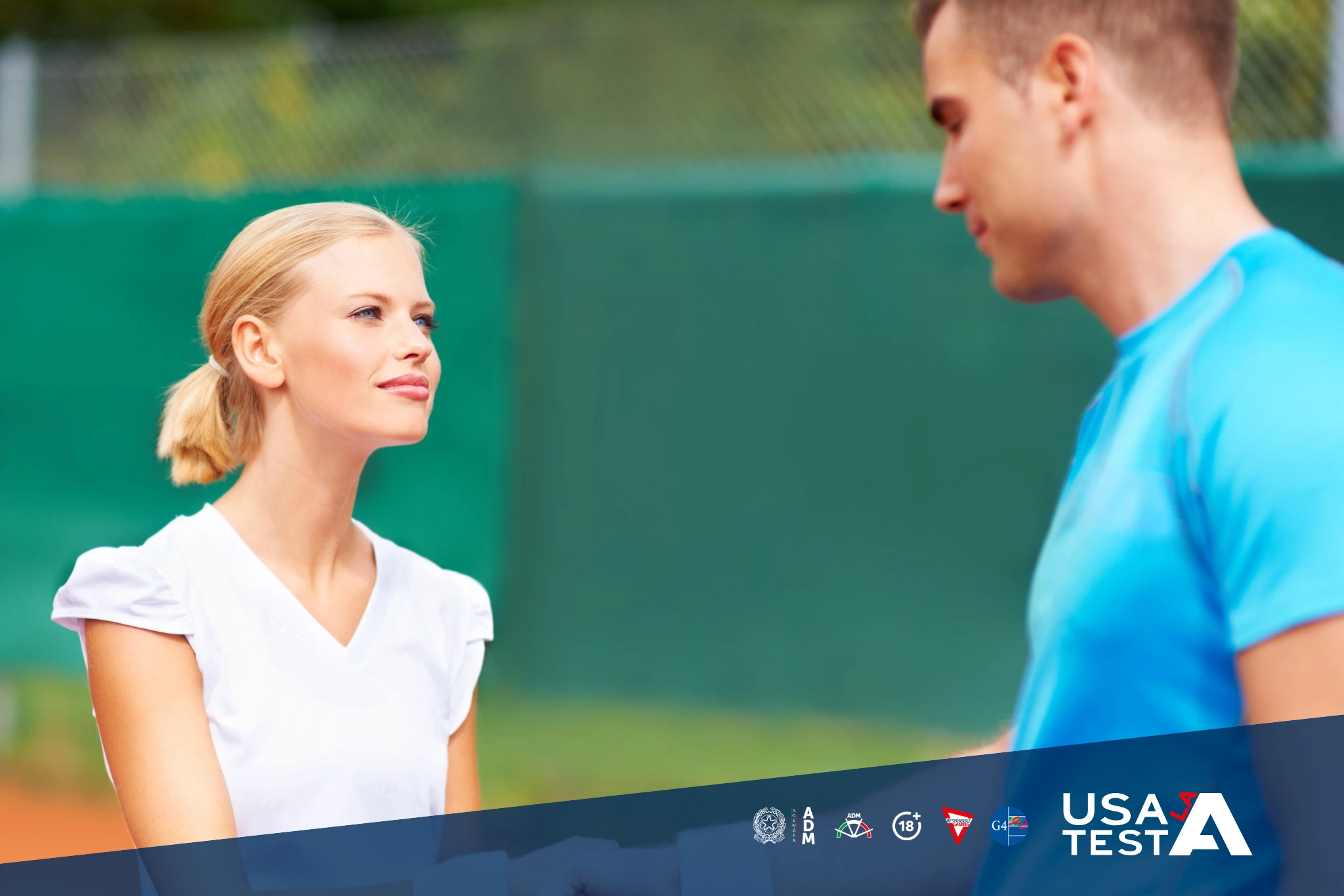 Due persone conversano su un campo da tennis, una indossa una maglietta bianca e l’altra una maglietta azzurra; sullo sfondo si vede la rete e il campo in terra rossa, con il logo “Usa la Testa” in basso a destra.