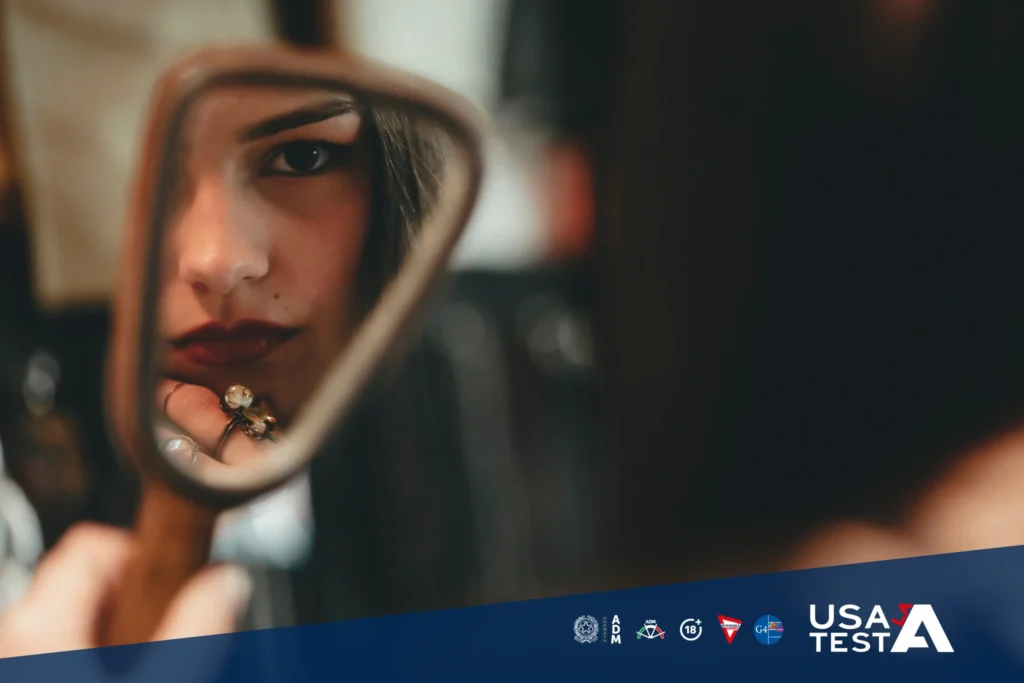 Persona che utilizza uno specchio come metafora di riflessione e come gesto simbolico di autoanalisi e consapevolezza legato al gioco responsabile, con loghi Usa la Testa.