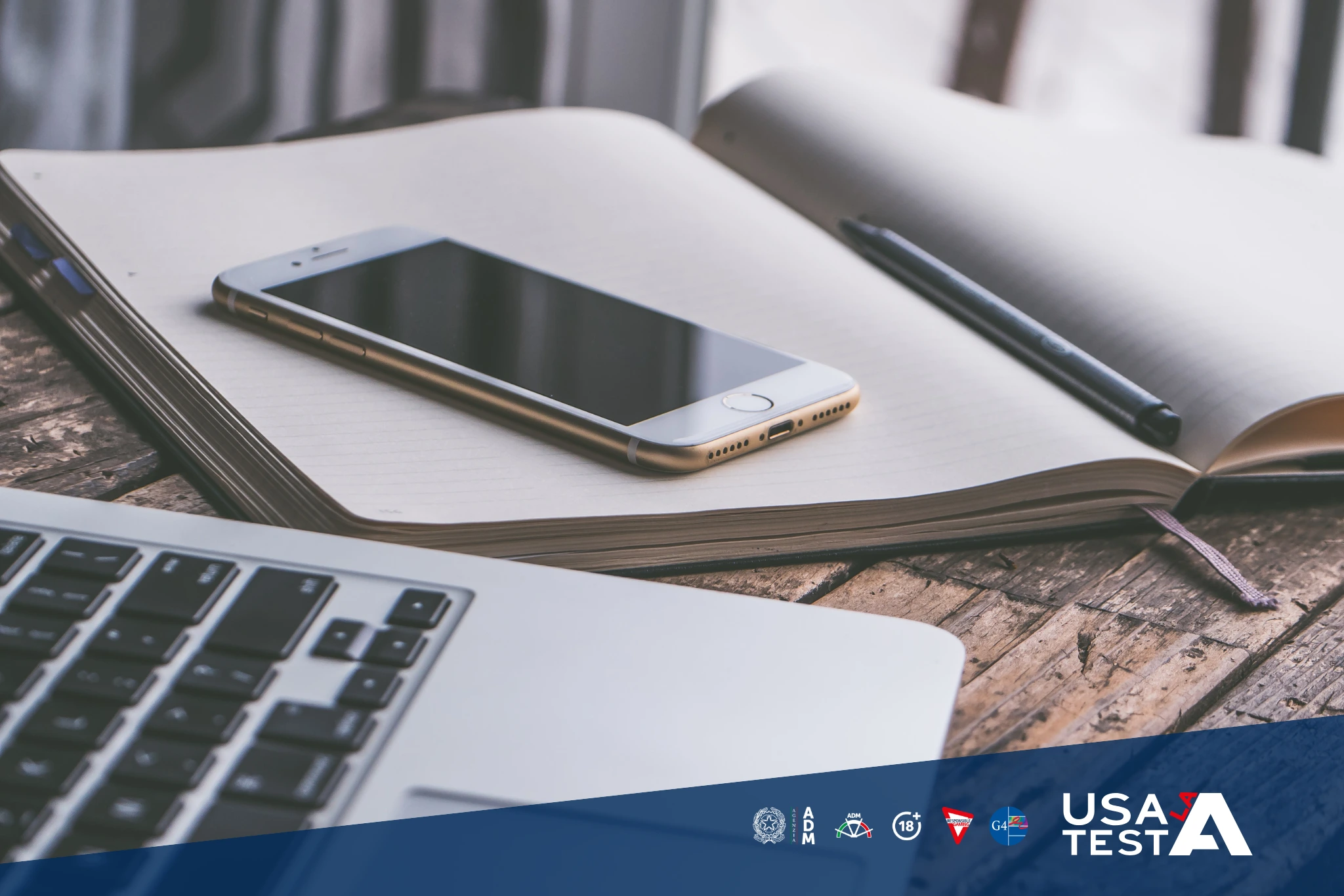 Notebook aperto con smartphone, penna e laptop su un tavolo di legno, concetto di diario digitale delle spese di gioco.